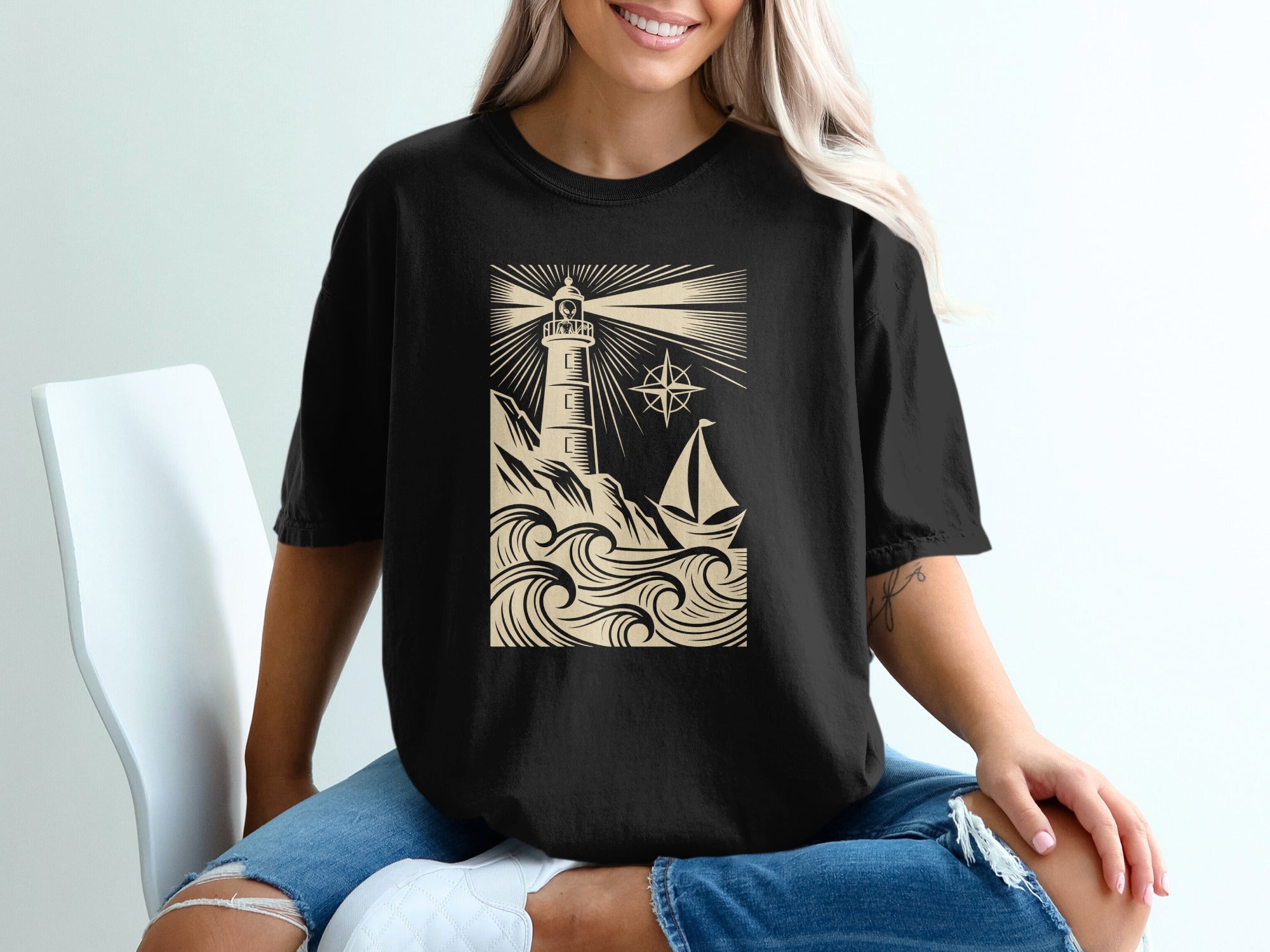 Black t-shirt with a cream lighthouse, waves, and sailboat design.