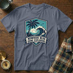 Grey t-shirt with shield graphic of palm tree, wave, and text "Nowhere Near Done Exploring."
