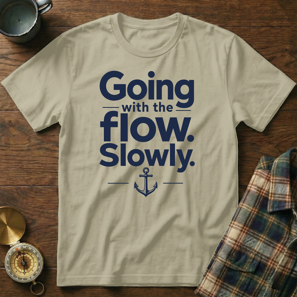 Beige crewneck t-shirt with navy blue text that reads Going with the flow. Slowly. and an anchor icon.