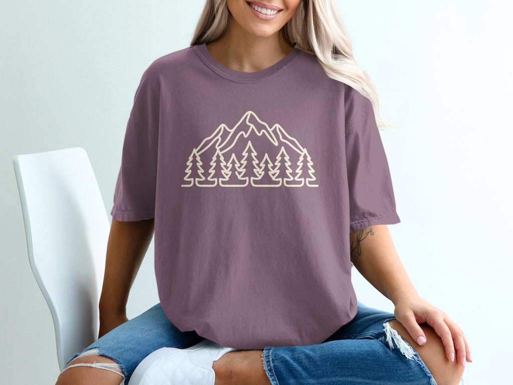 Purple t-shirt with a beige line drawing of mountains and trees.