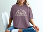 Purple t-shirt with a beige line drawing of mountains and trees.