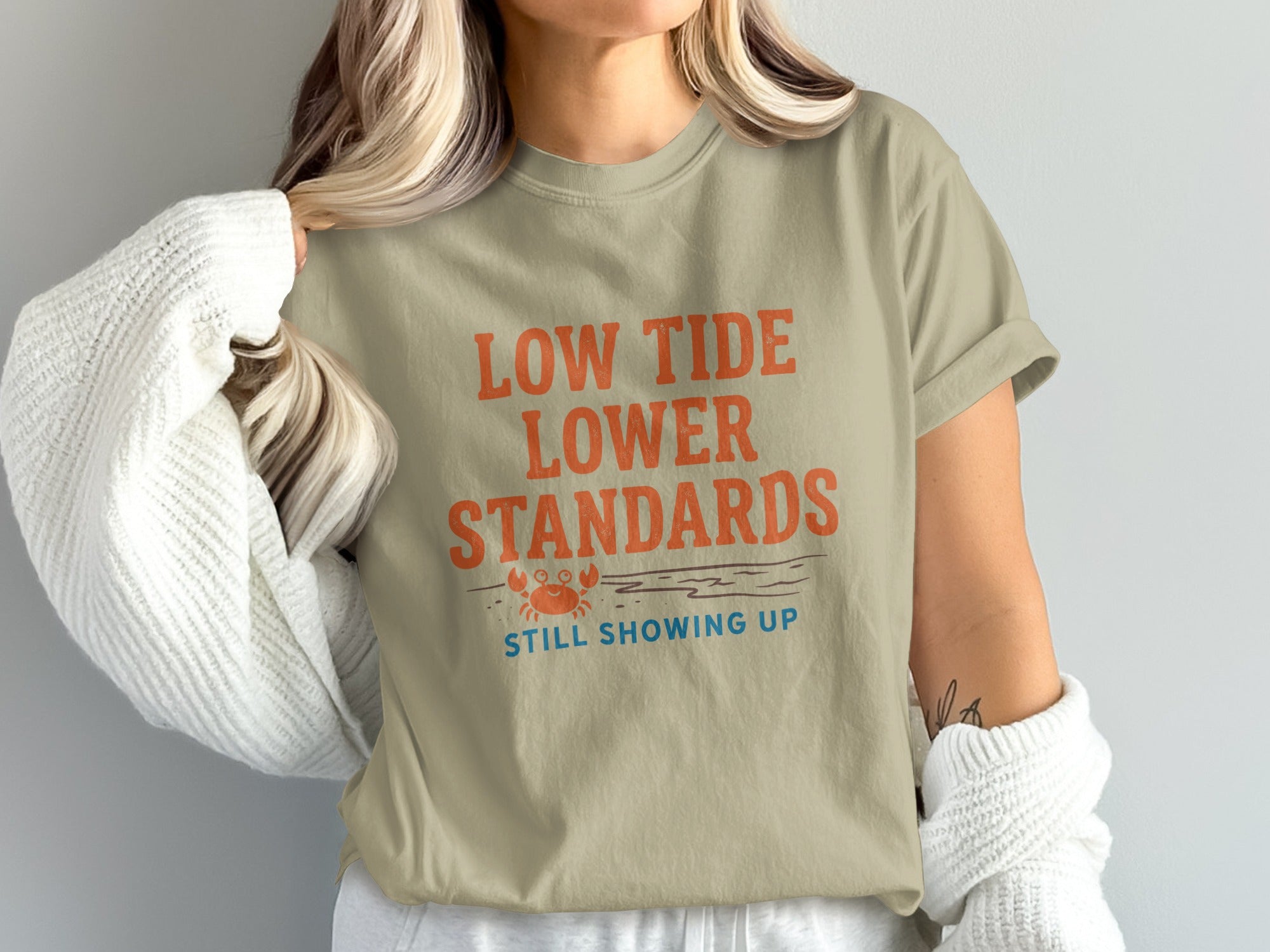 Beige t-shirt with text "LOW TIDE LOWER STANDARDS STILL SHOWING UP" and a crab graphic.