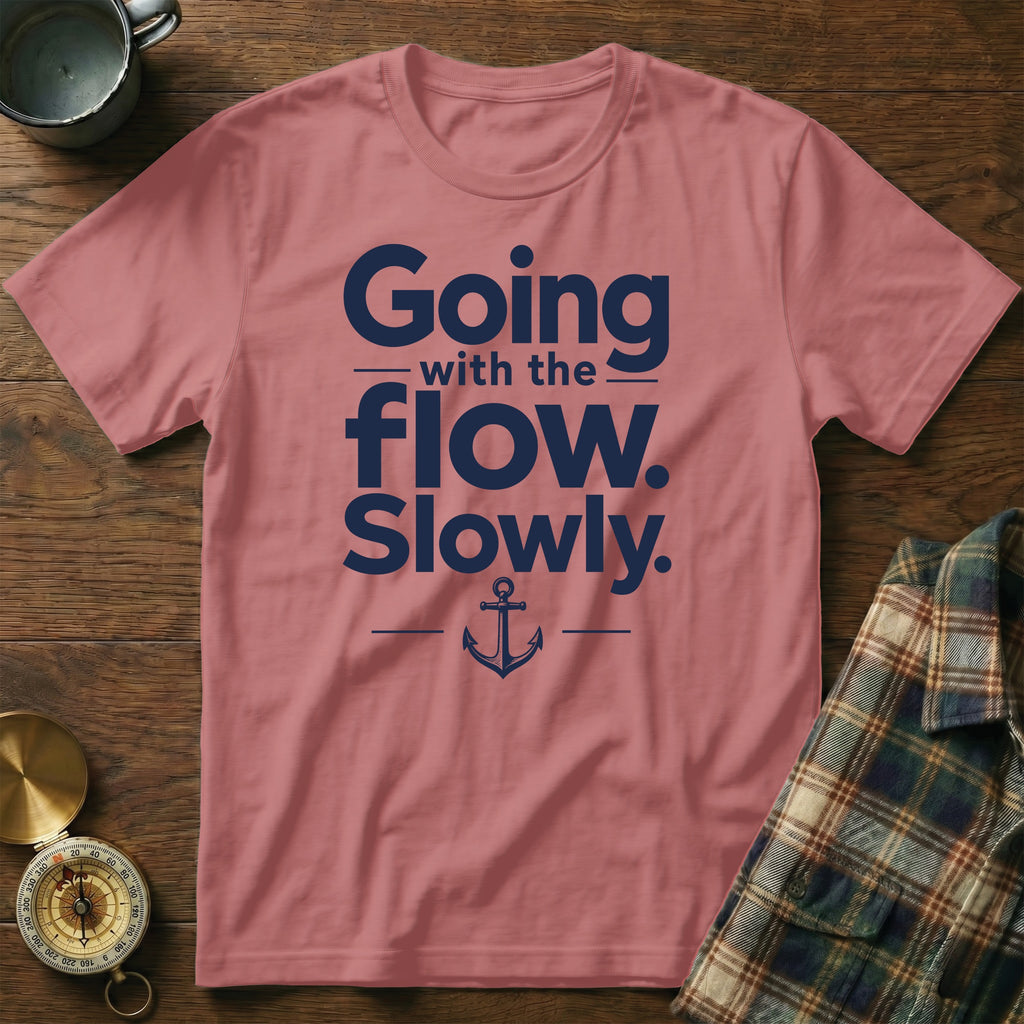 Dusty pink t-shirt featuring dark blue text reading Going with the flow. Slowly., accented with an anchor illustration.