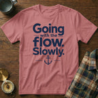 Dusty pink t-shirt featuring dark blue text reading Going with the flow. Slowly., accented with an anchor illustration.