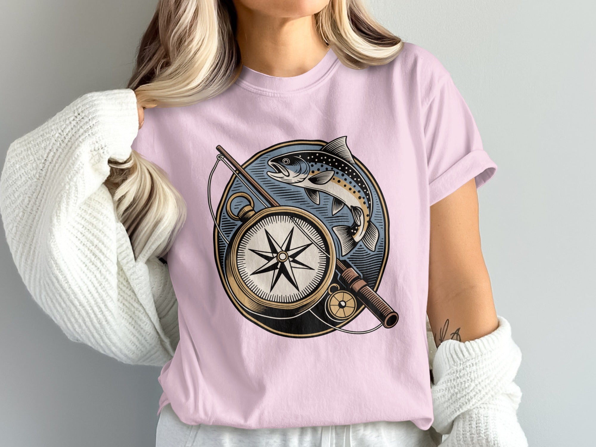 Pink t-shirt featuring a circular graphic with a compass, fishing rod, and fish.