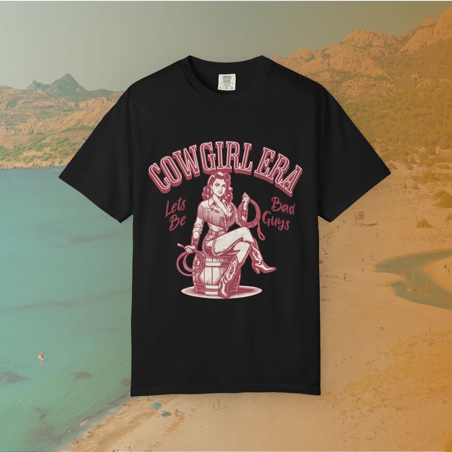 Cowgirl Era pinup T-shirt with a vintage-style illustration of a sassy cowgirl sitting on a barrel holding a lasso. The graphic includes the text "COWGIRL ERA" and "Lets Be Bad Guys.