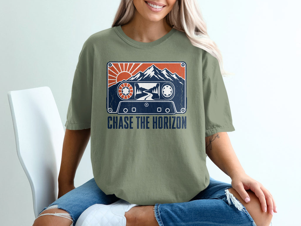 T-shirt with cassette tape graphic featuring mountains, sun, and text "CHASE THE HORIZON."