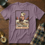 T-shirt with an eagle graphic wearing a hat and striped shirt, surfing. Text reads "UNBOTHERED COASTAL AMERICANA".
