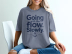 A person wearing a grey t-shirt featuring the text "Going with the flow. Slowly." and an anchor graphic.