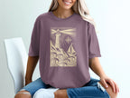 Purple t-shirt with lighthouse, sailboat, and compass design.