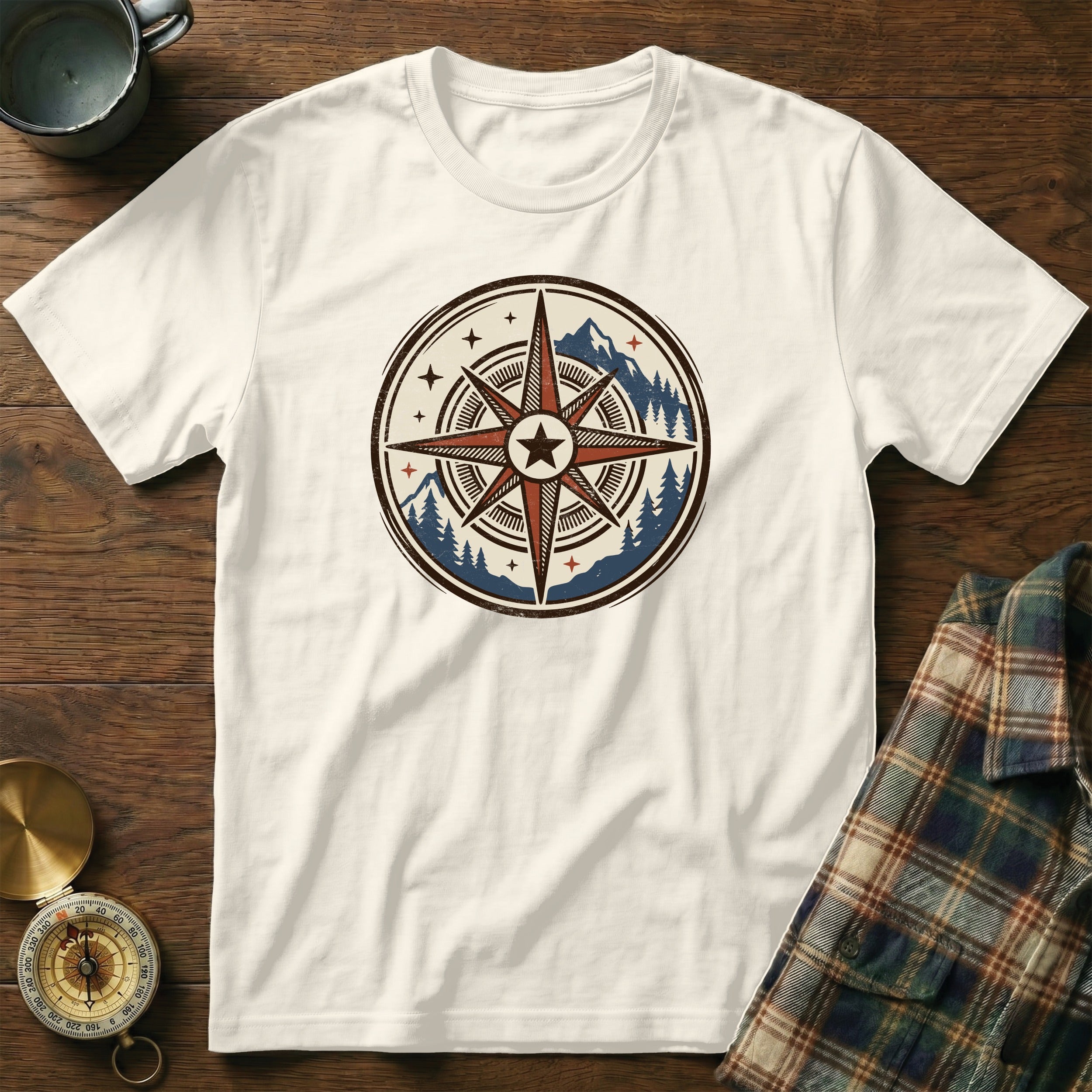 White t-shirt with a circular compass graphic featuring mountains and pine trees.