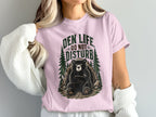 Pink t-shirt with bear graphic and text "DEN LIFE DO NOT DISTURB"