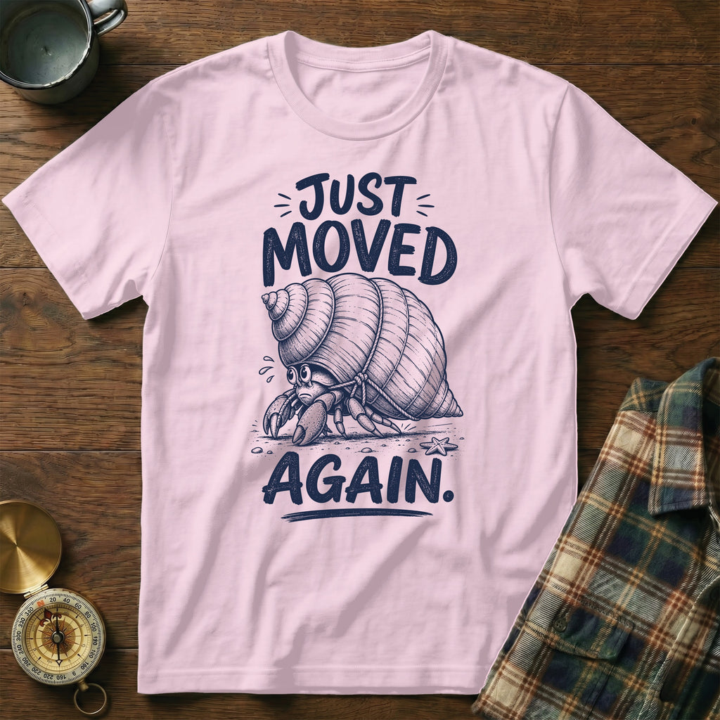 Pink t-shirt with a sketch of a sad hermit crab and text "JUST MOVED AGAIN."