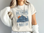 Cream t-shirt with "The mountains are calling, the wifi and internet is terrible, I must go" text and mountain graphic.