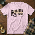 Pink t-shirt with "ROUGHING IT." text and a camp chair by the ocean.