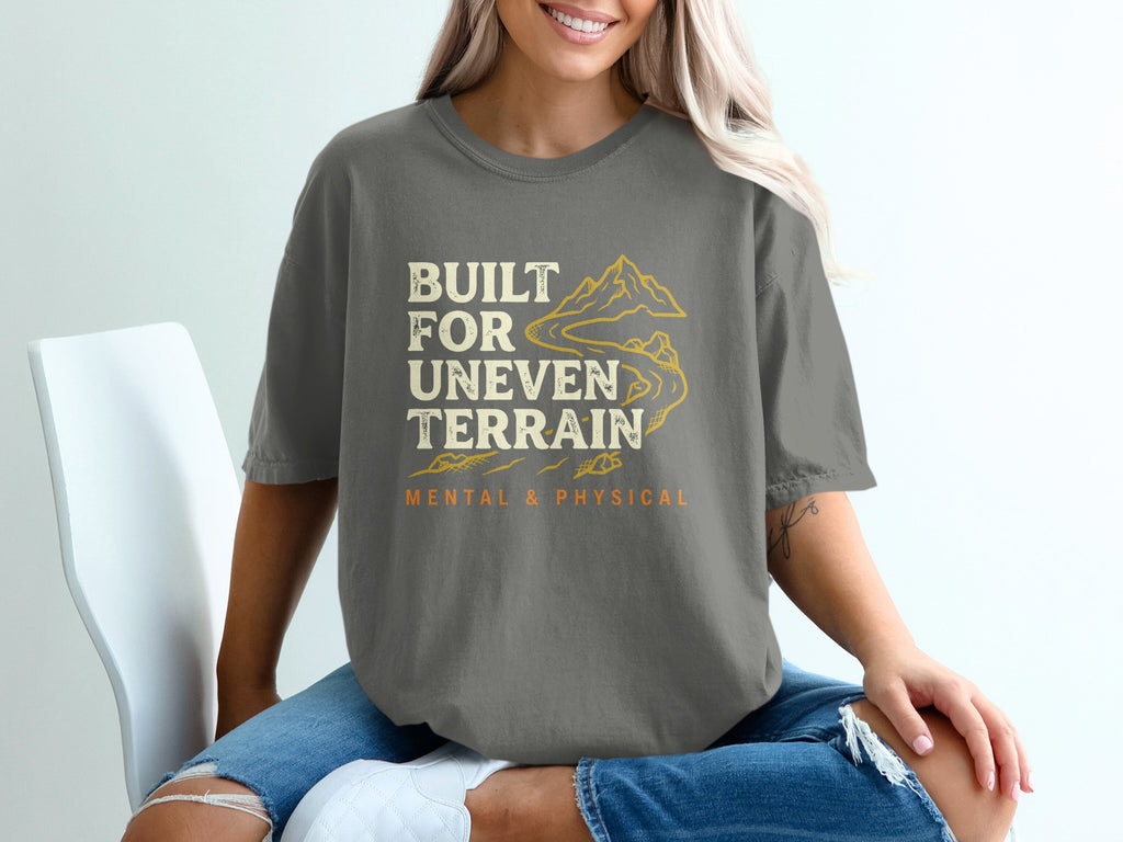 Gray t-shirt with "Built for Uneven Terrain" and mountains graphic.