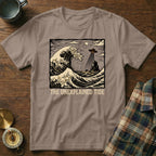 T-shirt graphic: UFO above crashing waves and rocky island, "The Unexplained Tide."