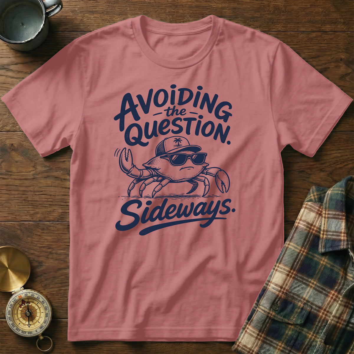 Dusty pink t-shirt featuring a cartoon crab wearing sunglasses and a cap, with blue text that reads avoiding the question sideways.