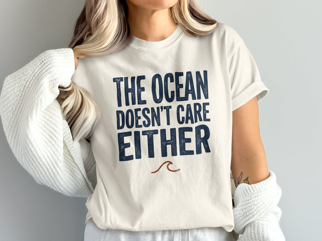 Cream t-shirt with dark blue text: "The Ocean Doesn't Care Either".