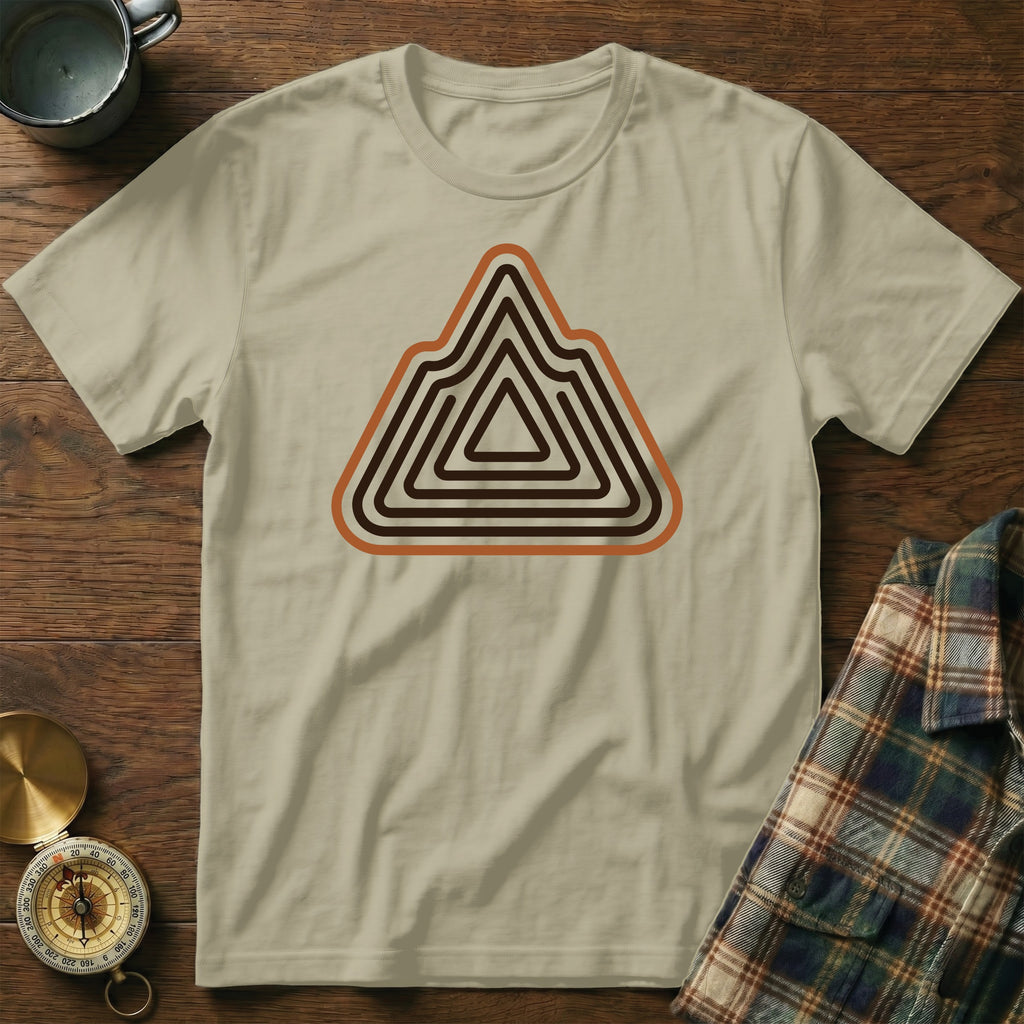Light tan t-shirt with a mountain-shaped graphic in brown and orange concentric lines.