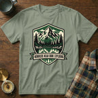 Green t-shirt with mountain lake graphic and "Nowhere Near Done Exploring" text.