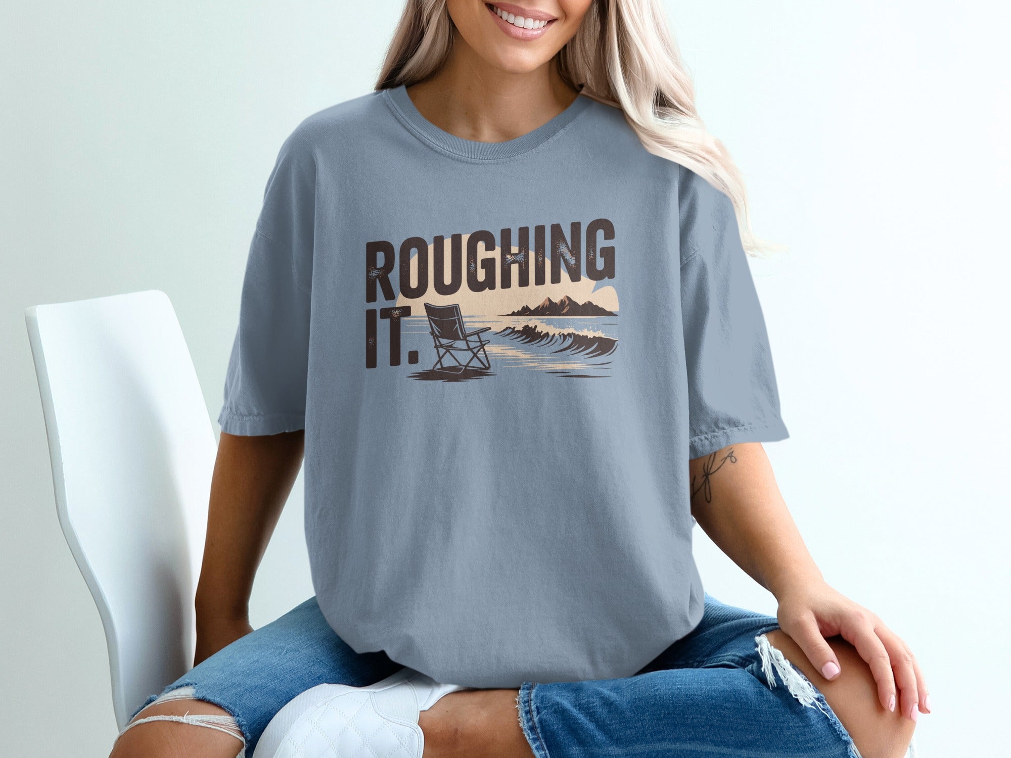Light blue t-shirt with "ROUGHING IT." text and a beach scene graphic.