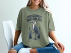 Green t-shirt with a heron graphic and "Professionally Motionless" text.