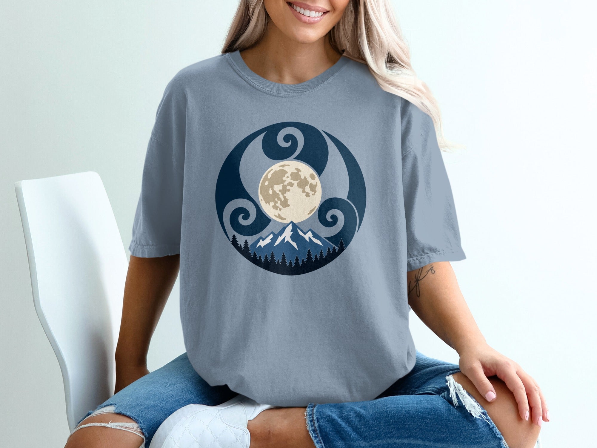Grey t-shirt with circular moon, mountains, and trees graphic design.