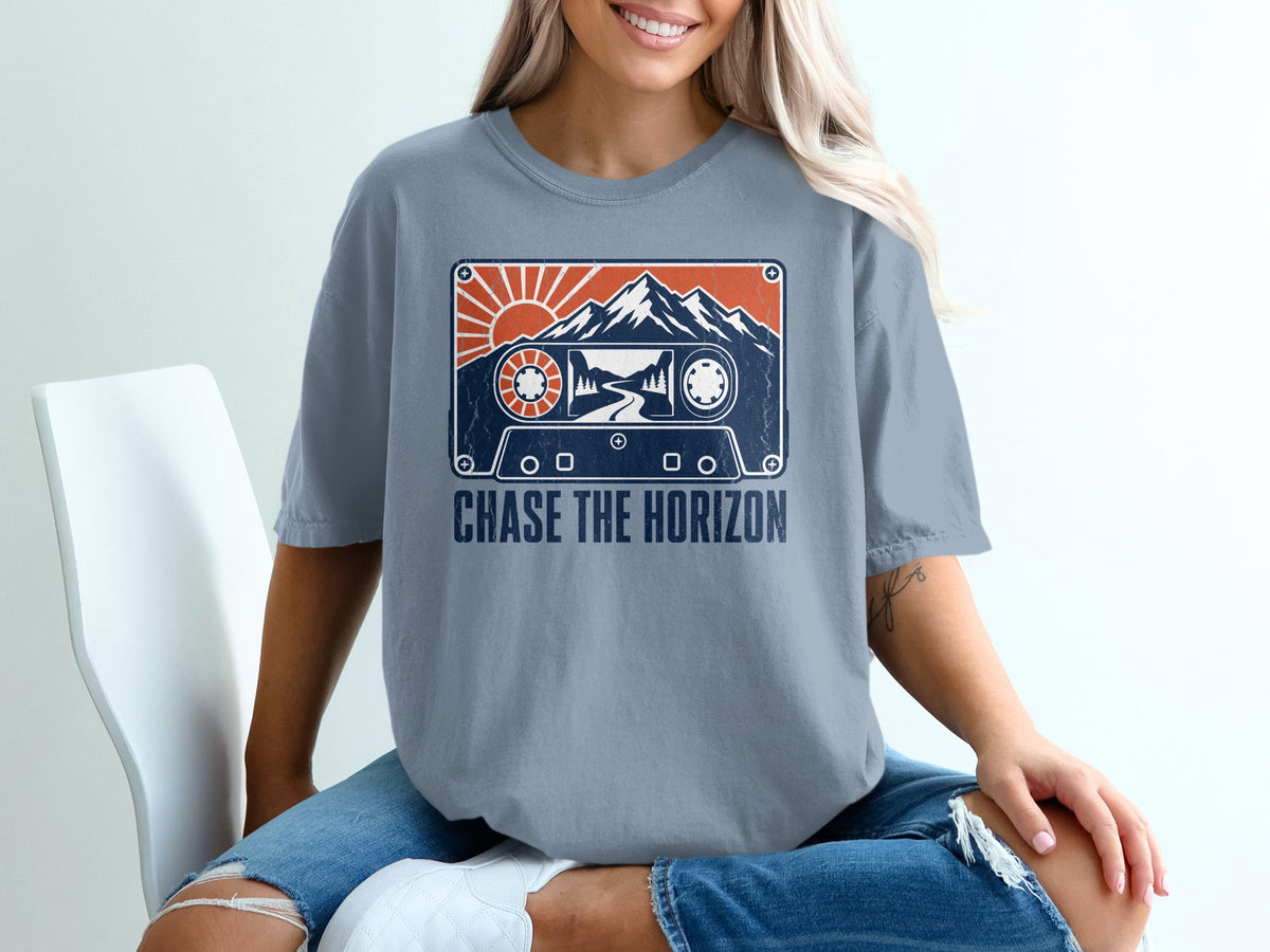 T-shirt with cassette tape graphic featuring mountains, sun, and text "Chase the Horizon".