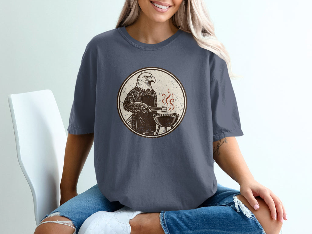 Eagle wearing apron grilling with tongs on a barbecue in a circular design.