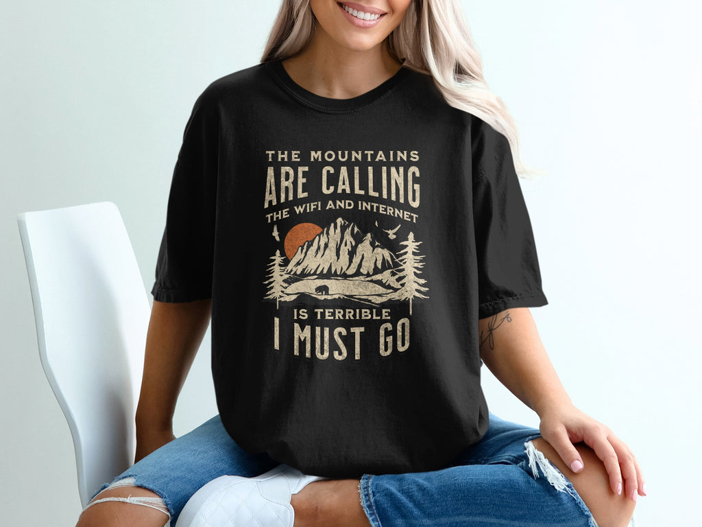Black t-shirt with "The mountains are calling, the WiFi and internet is terrible I must go" graphic.