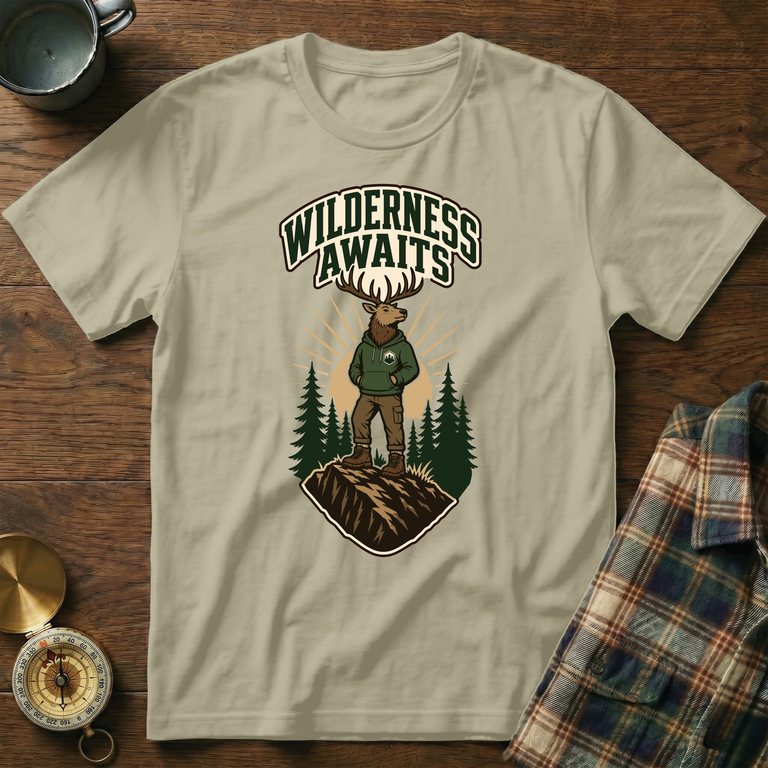 T-shirt graphic of elk wearing hoodie, "Wilderness Awaits" text, pine trees.