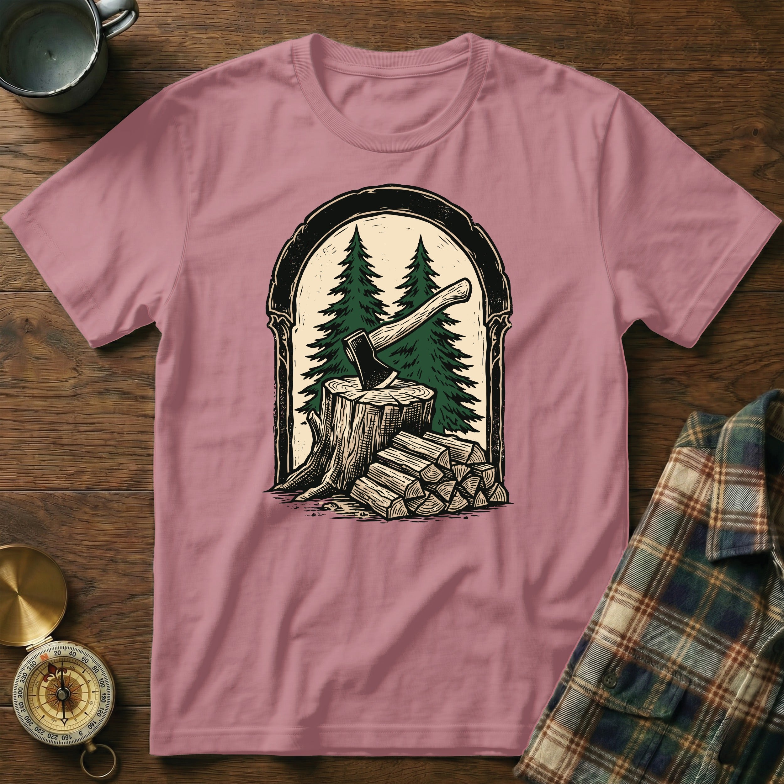 T-shirt featuring an axe in a tree stump with firewood and pine trees.