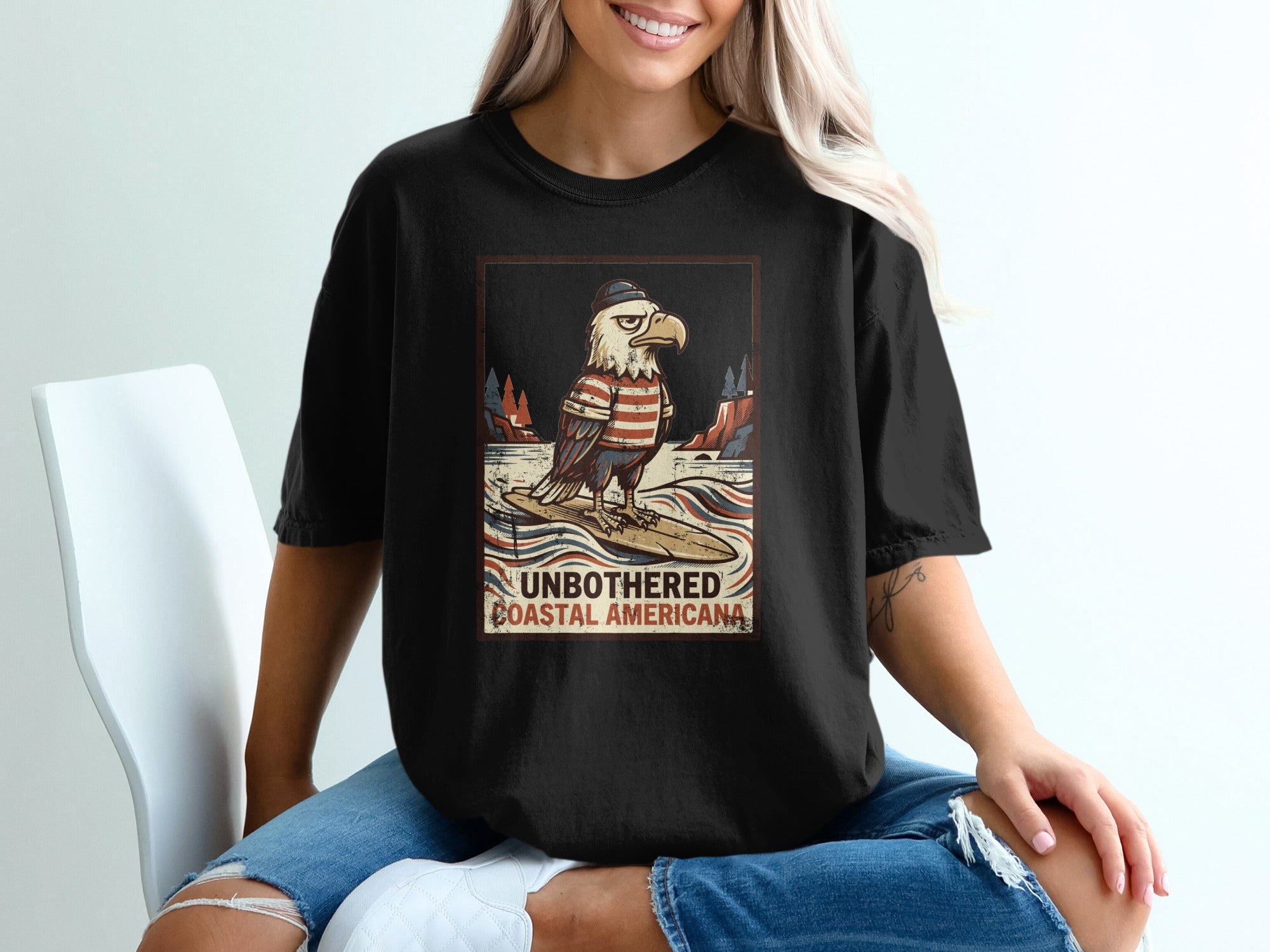 Eagle wearing sweater and hat surfing with text "UNBOTHERED COASTAL AMERICANA."