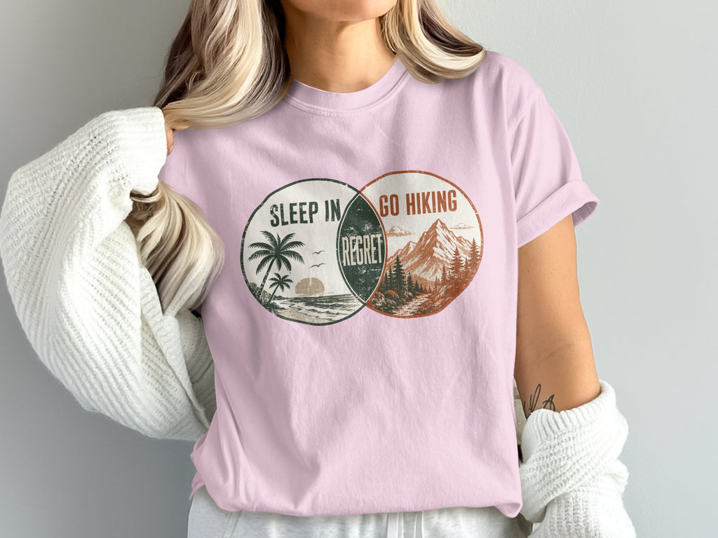 Pink t-shirt with circular graphic of beach and mountains, reading "Sleep In Regret Go Hiking".