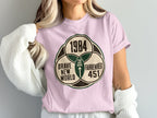 Pink t-shirt with graphic that says "1984", "Brave New World", and "Fahrenheit 451".