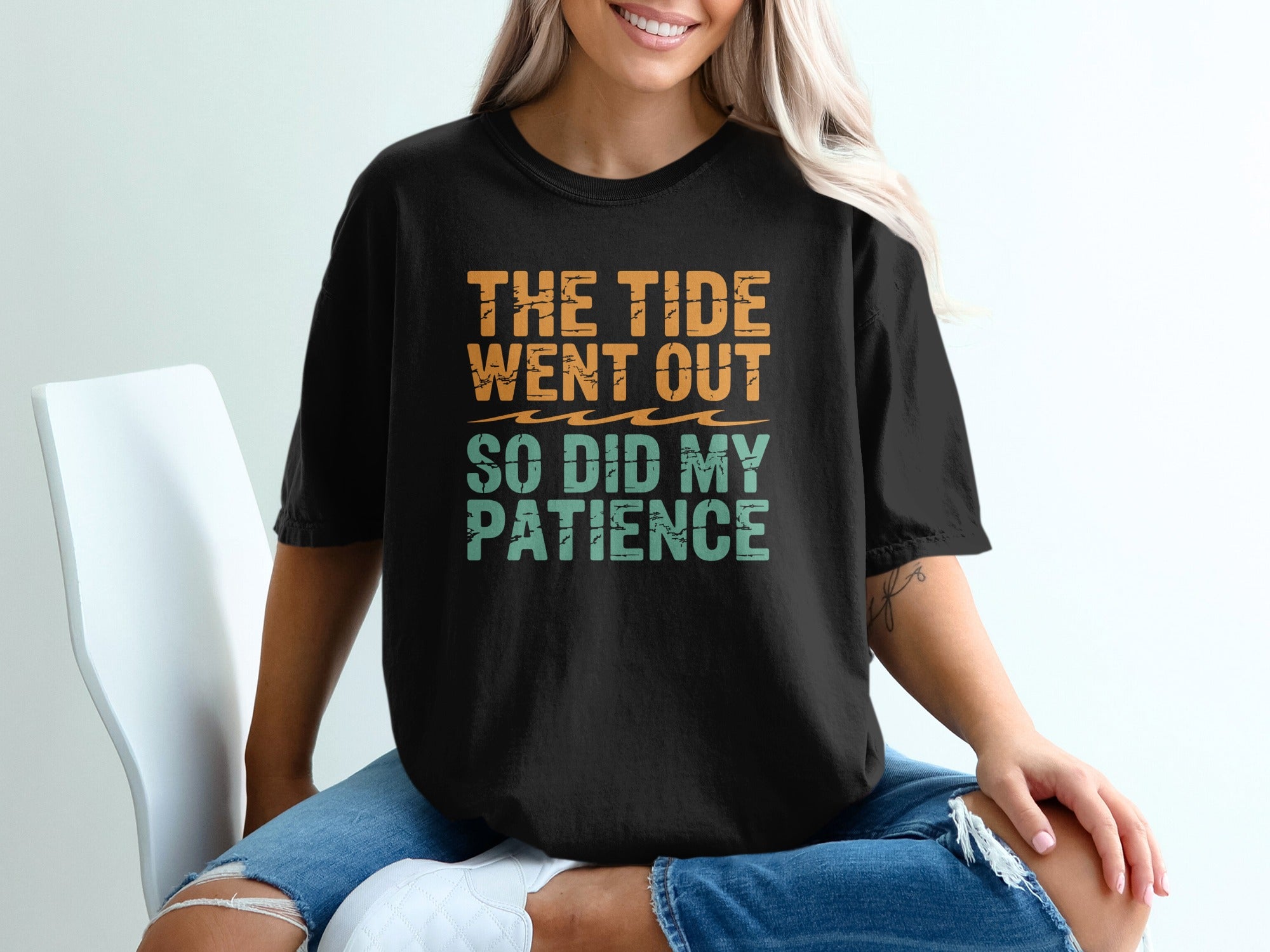 Black t-shirt with orange and teal text reading "THE TIDE WENT OUT SO DID MY PATIENCE".