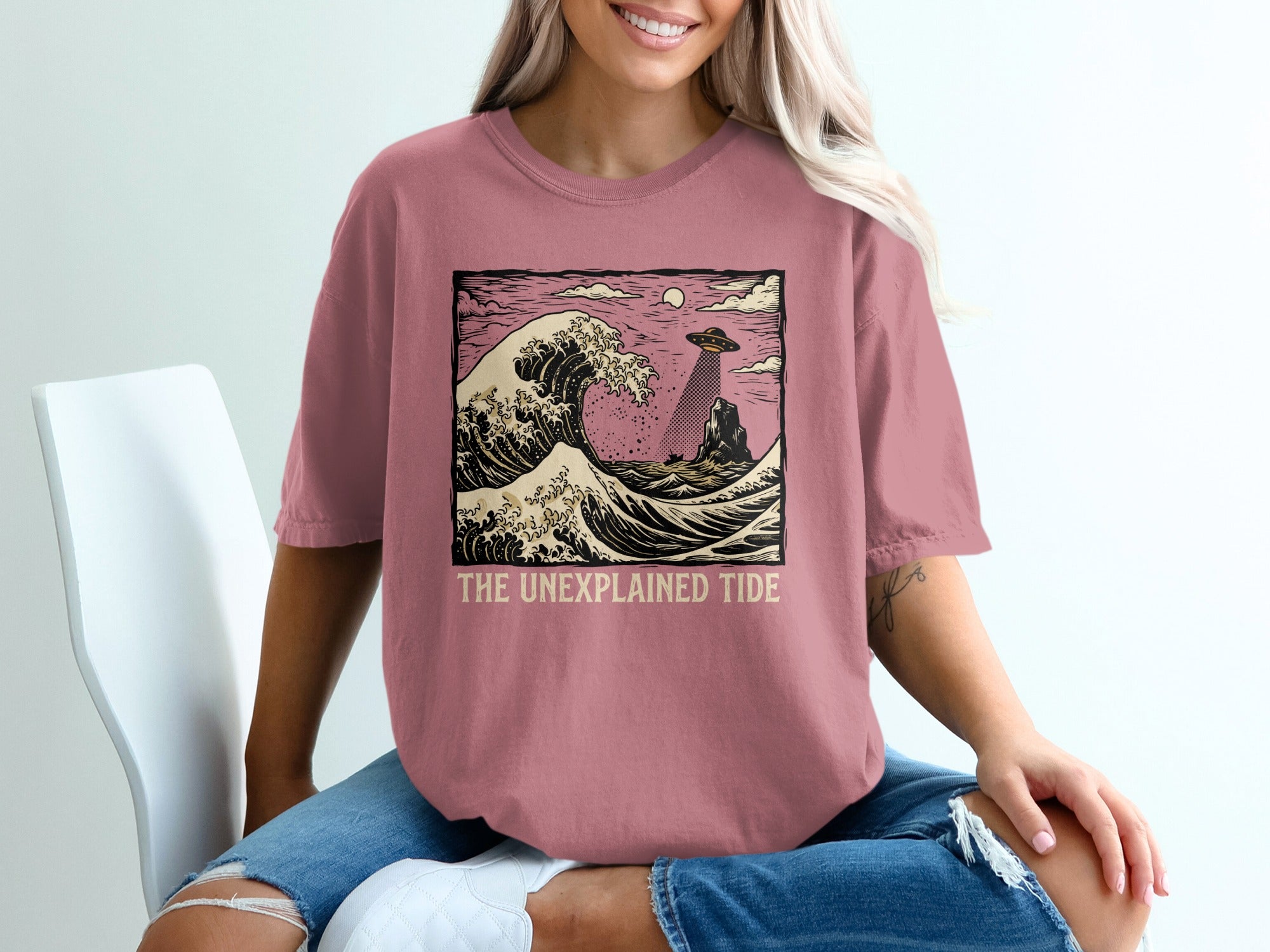 Unexplained Tide t-shirt graphic with a UFO hovering over a large wave.