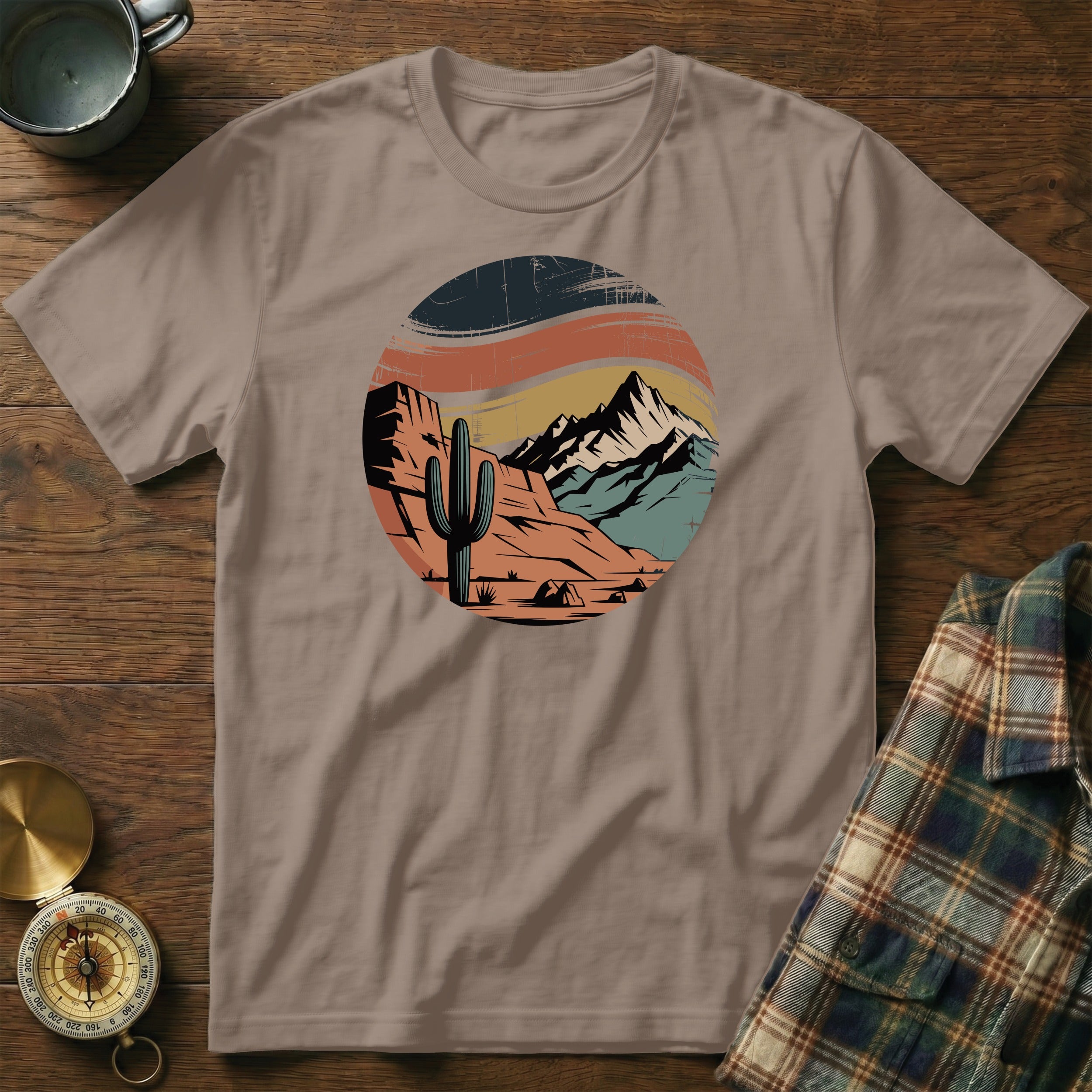 T-shirt featuring desert landscape with cactus, mountains, and sunset design.