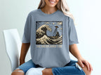 T-shirt graphic with a wave, UFO, and text "THE UNEXPLAINED TIDE".