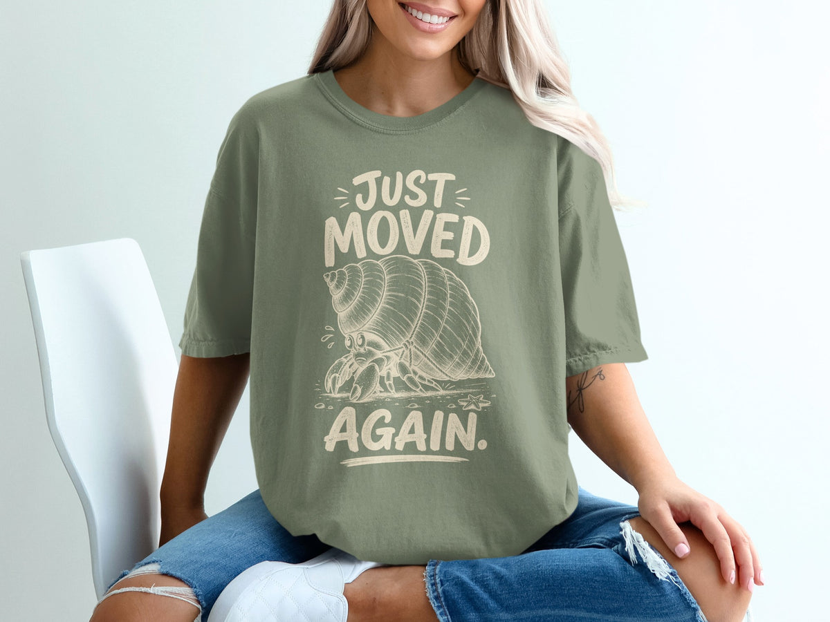 Green t-shirt with a hermit crab graphic and text "JUST MOVED AGAIN."