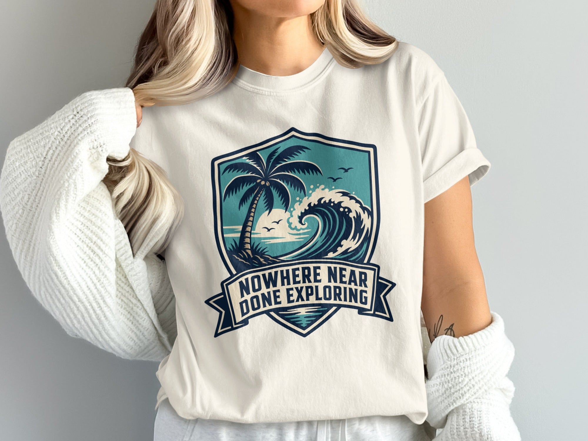 T-shirt with ocean wave, palm tree and banner text "NOWHERE NEAR DONE EXPLORING".
