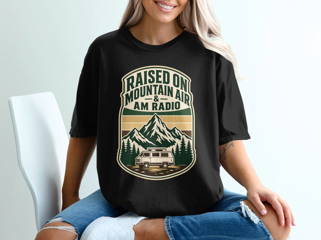 Black t-shirt with "Raised On Mountain Air & AM Radio" mountain and van graphic.