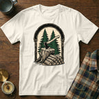 T-shirt with graphic of axe in tree stump with stacked firewood and evergreen trees.