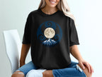 Black t-shirt with a circular design featuring a moon, mountains, and swirling patterns.