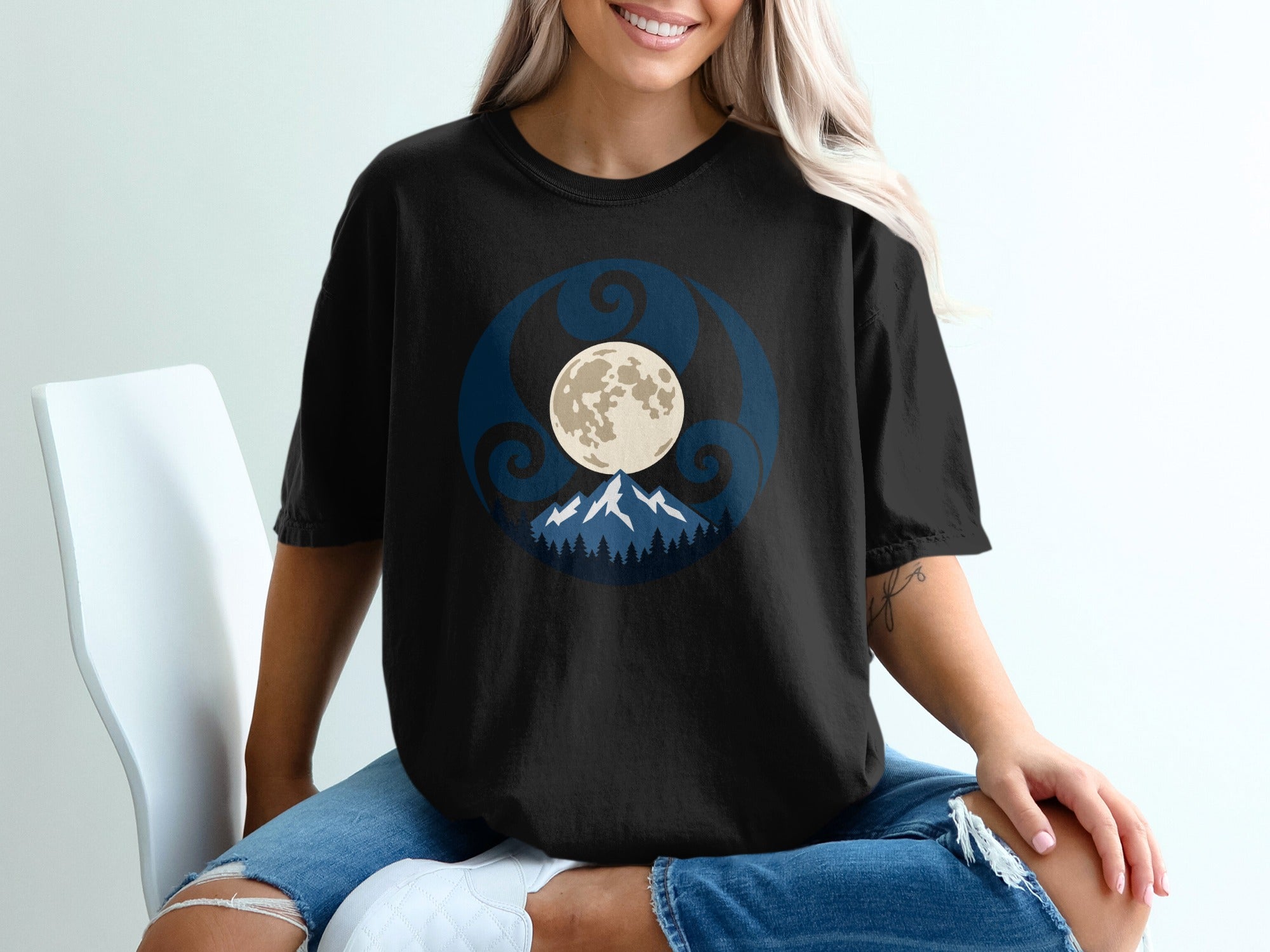 Black t-shirt with a circular design featuring a moon, mountains, and swirling patterns.