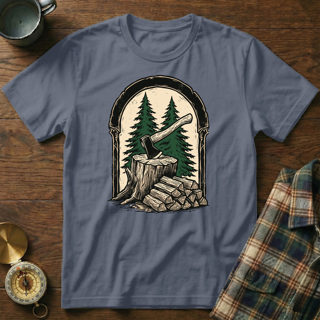 T-shirt graphic of an axe in a tree stump with stacked firewood and pine trees.