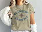 Khaki t-shirt with blue "HOMEGROWN WANDERER" text and a compass graphic.