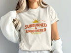 T-shirt with "Sunburned & Unbothered" text and a sun graphic.