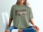 Olive green t-shirt with "ROUGHING IT." text and beach scene graphic.